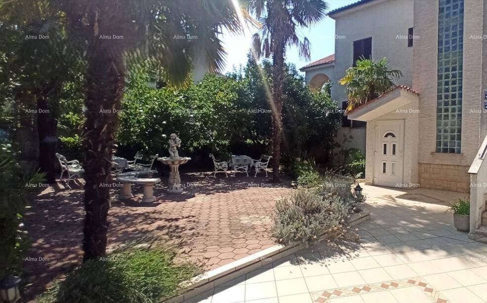 Mediterraner Garten mit Palmen, gepflasterter Terrasse, Gartenmöbeln und einem dekorativen Brunnen.
