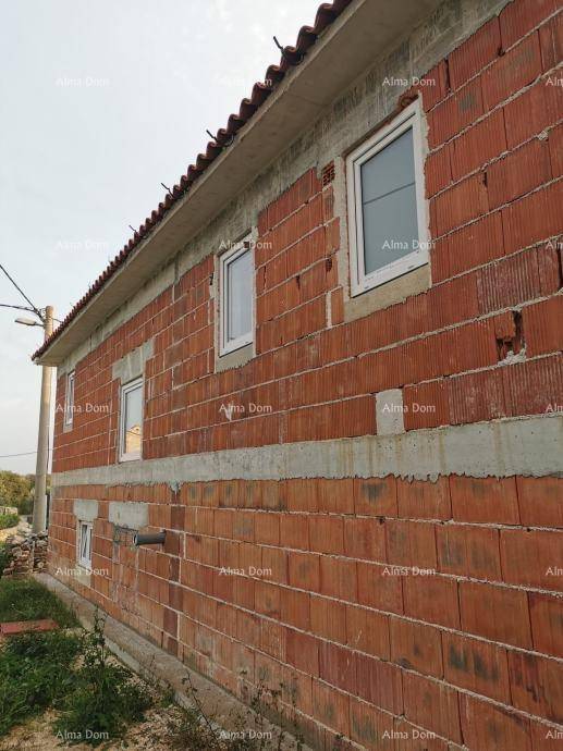 Nahaufnahme der roten Ziegelwand eines Rohbaus mit weißen Fenstern und Dachüberstand.