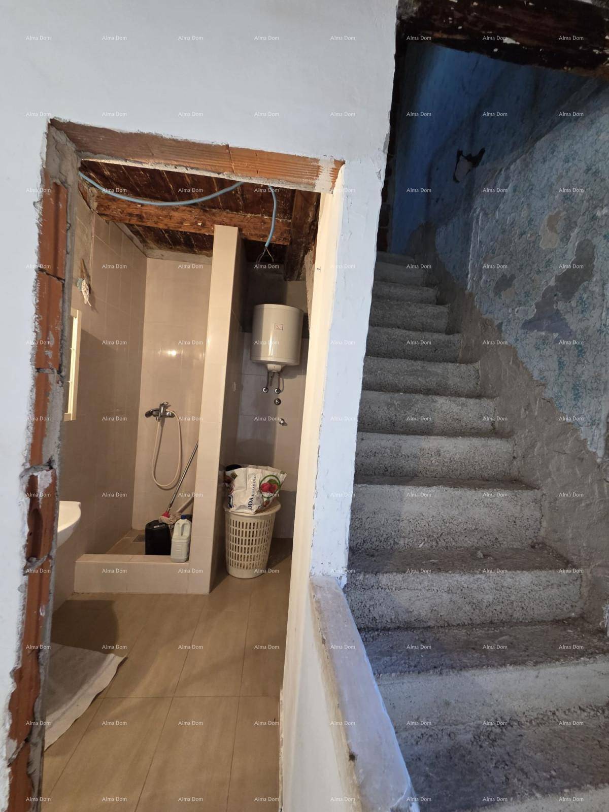 Einfaches Badezimmer mit Duschbereich und Boiler, neben einer rohen Steintreppe.