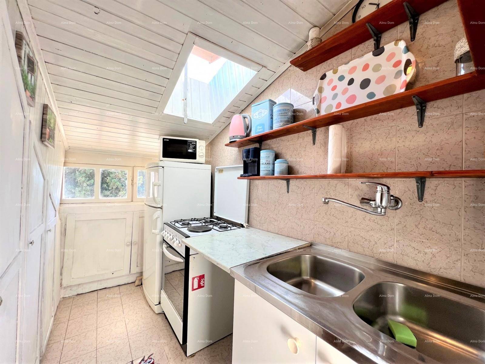Kleine Küche mit Fliesenboden, Holzdecke, Dachfenster und einfachen Geräten.
