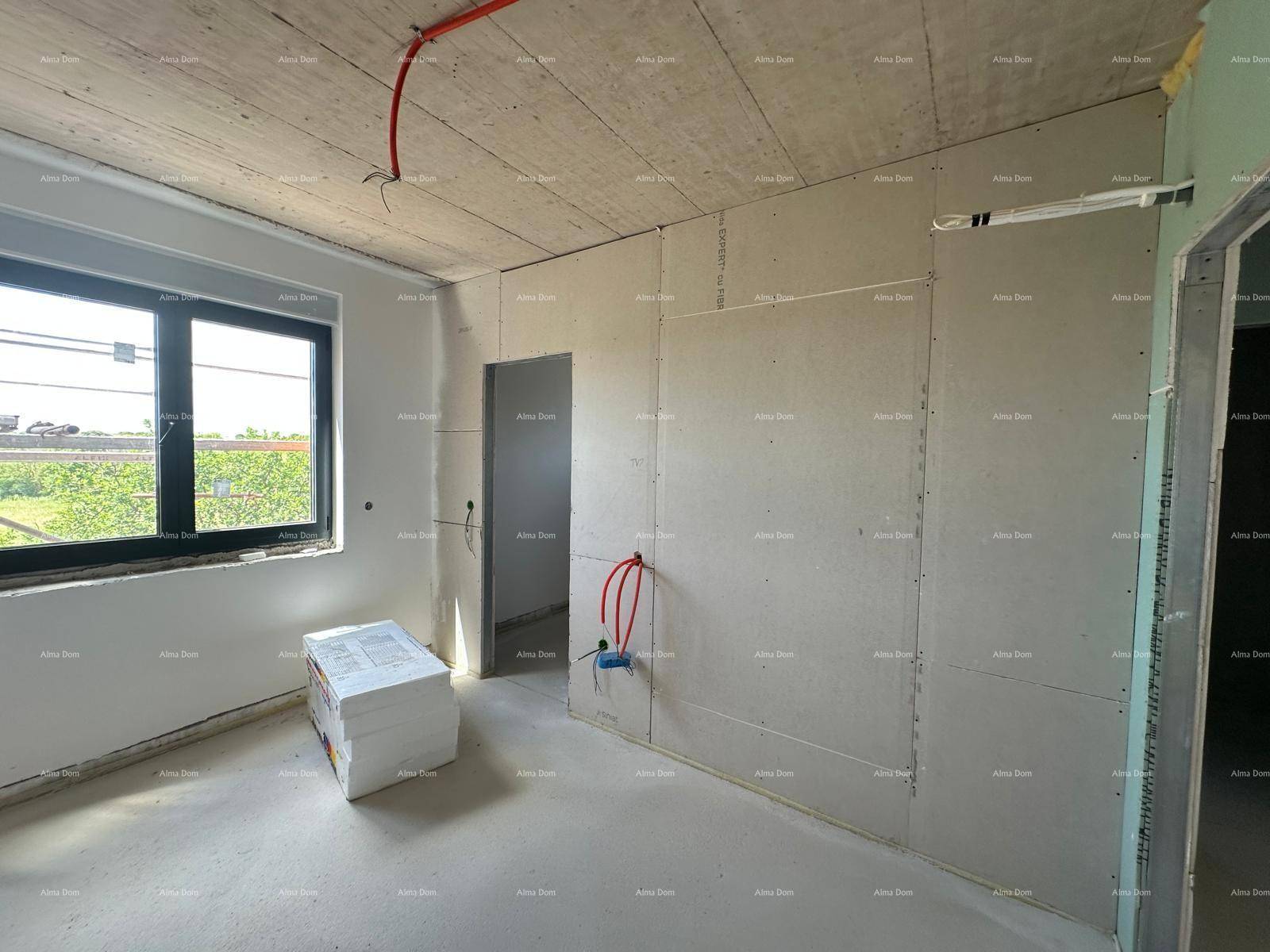 Raum im Rohbau mit Trockenbauwänden, Beton-Decke und einem Fenster, Dämmmaterial liegt bereit.