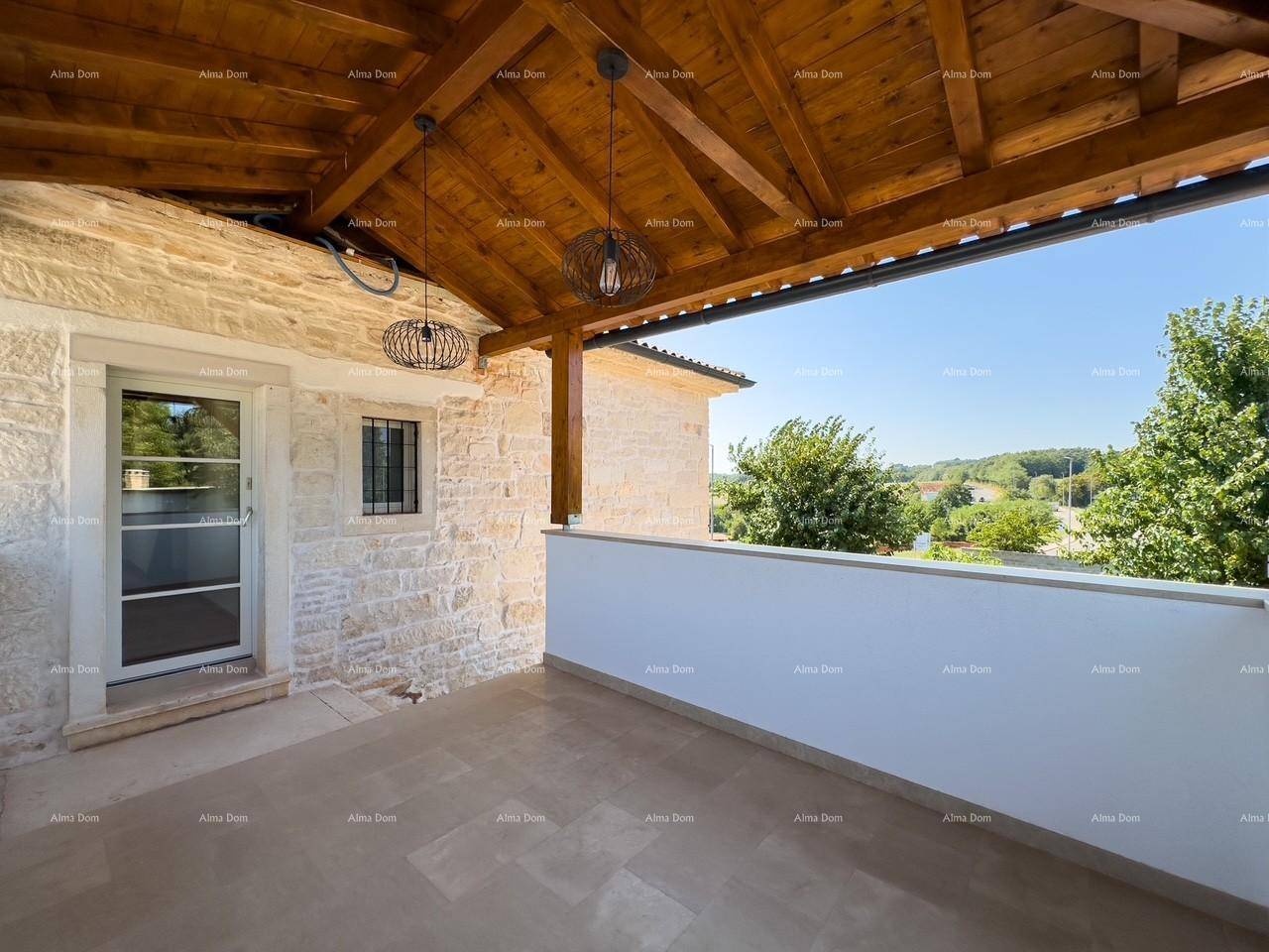 Überdachte Terrasse mit Steinwand und Zugang zum Haus, umgeben von viel Grün.