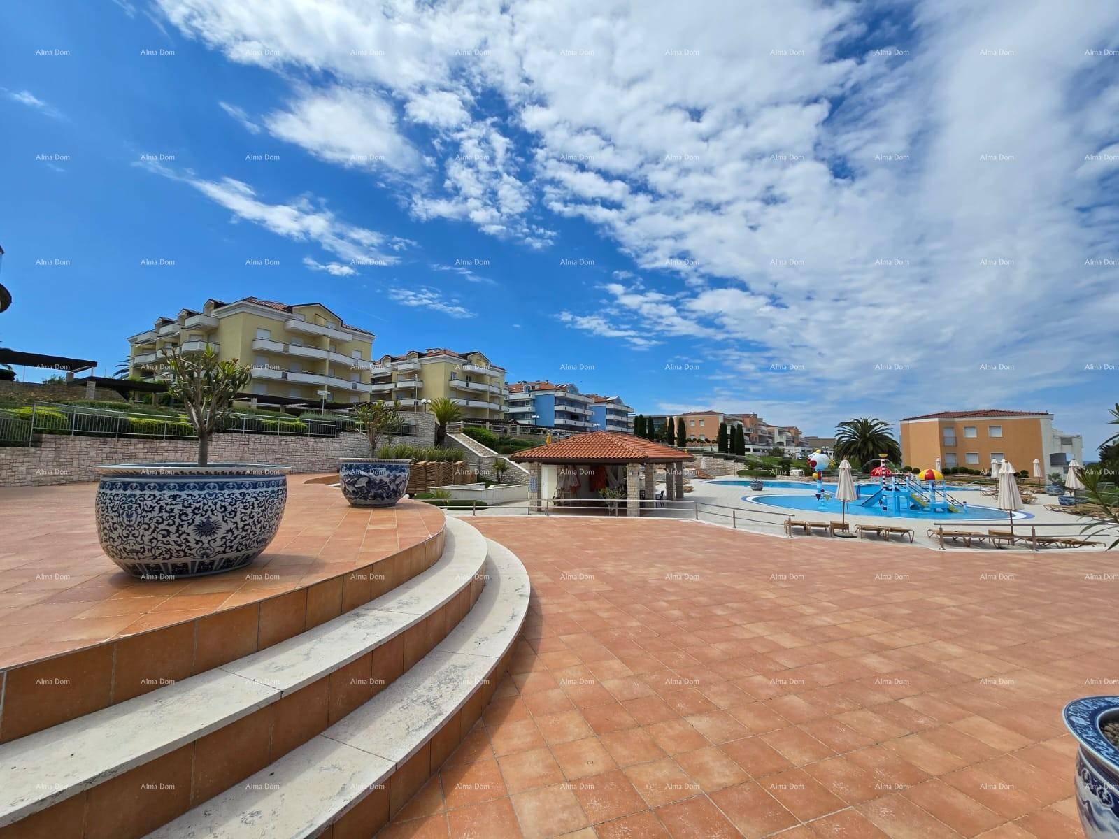 Weitläufiger gepflasterter Außenbereich mit Stufen und dekorativen Pflanzgefäßen, Blick zum Pool.