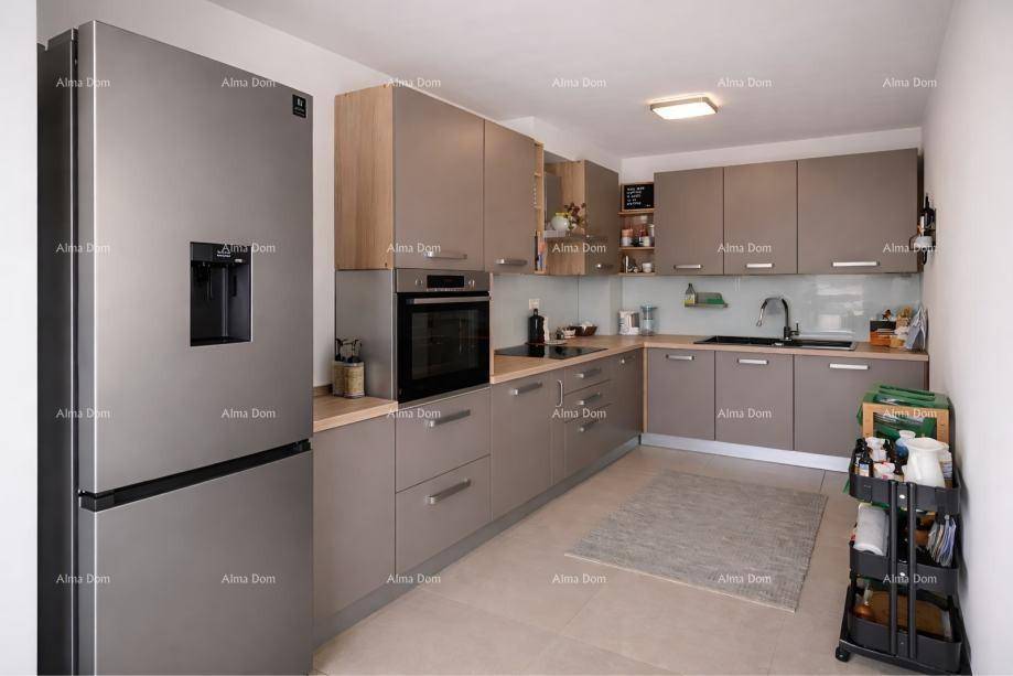 Moderne Küche mit grauen Schränken, Holzarbeitsplatten und integrierten Edelstahlgeräten, inklusive großem Kühlschrank.