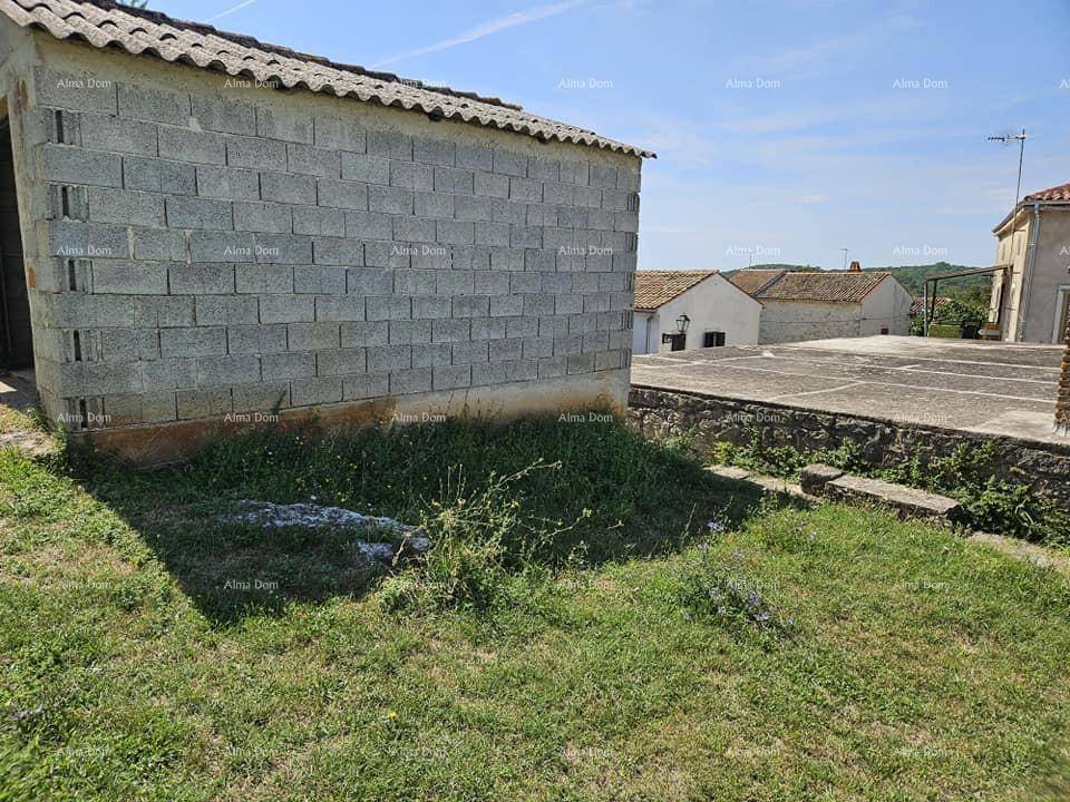 Seitenansicht eines Gebäudes aus Betonblöcken auf einem grasbewachsenen Grundstück mit Blick auf weitere Häuser.