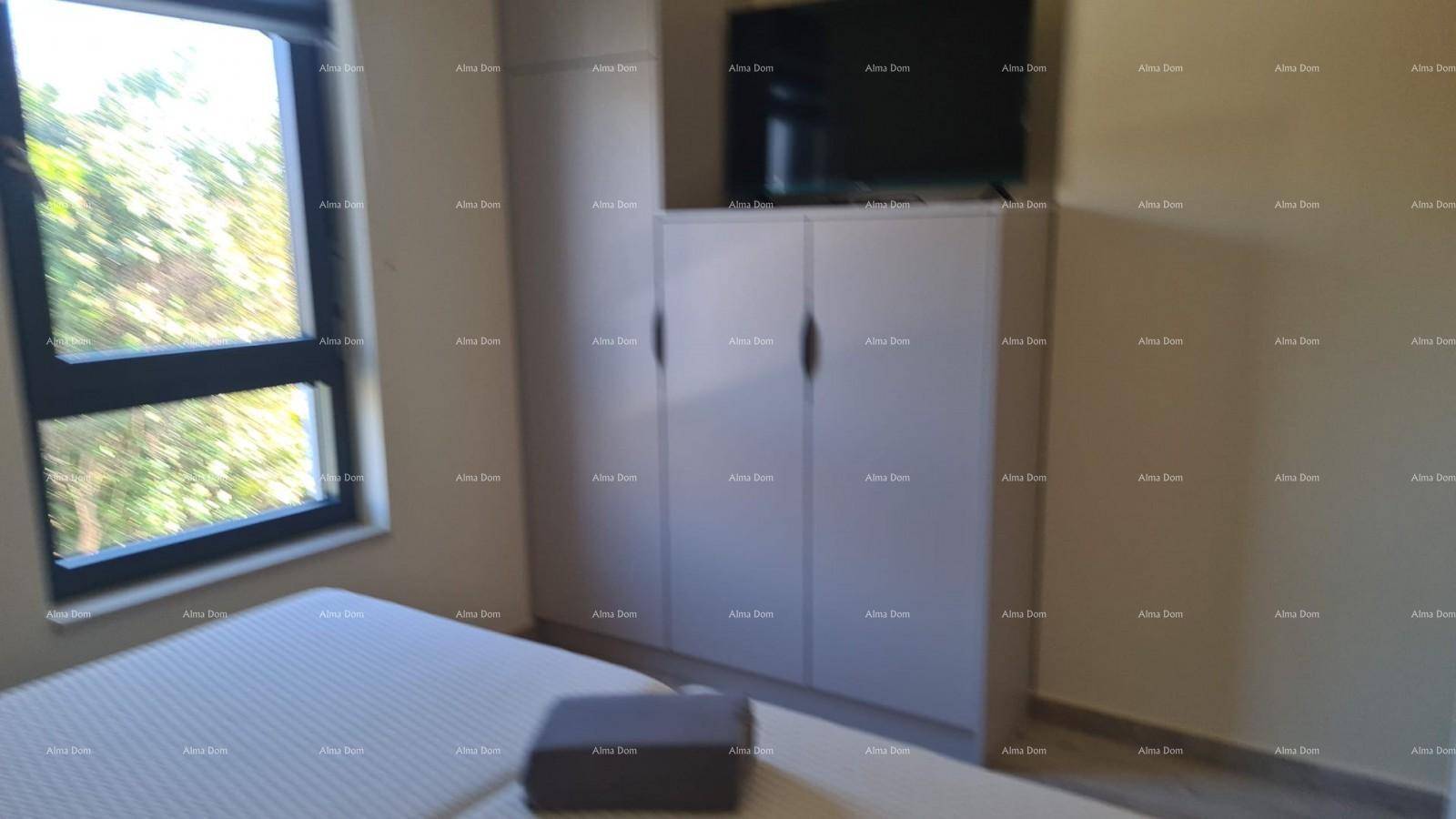 Schlafzimmer mit weißem Kleiderschrank, Fernseher und Fenster, das den Raum erhellt.