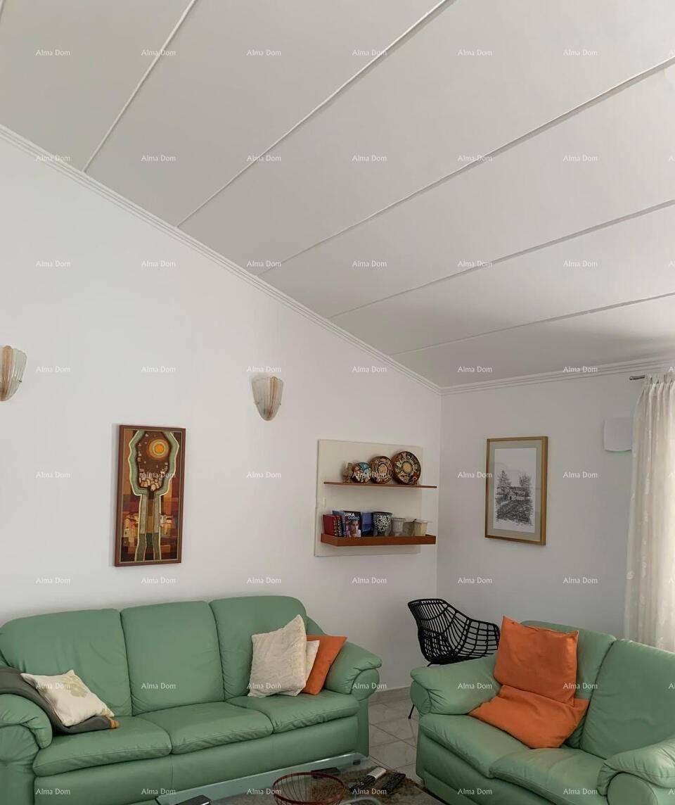 Gemütlicher Wohnbereich mit bequemen grünen Sofas und schrägen Decken, dekoriert mit Wandbildern und Regalen.