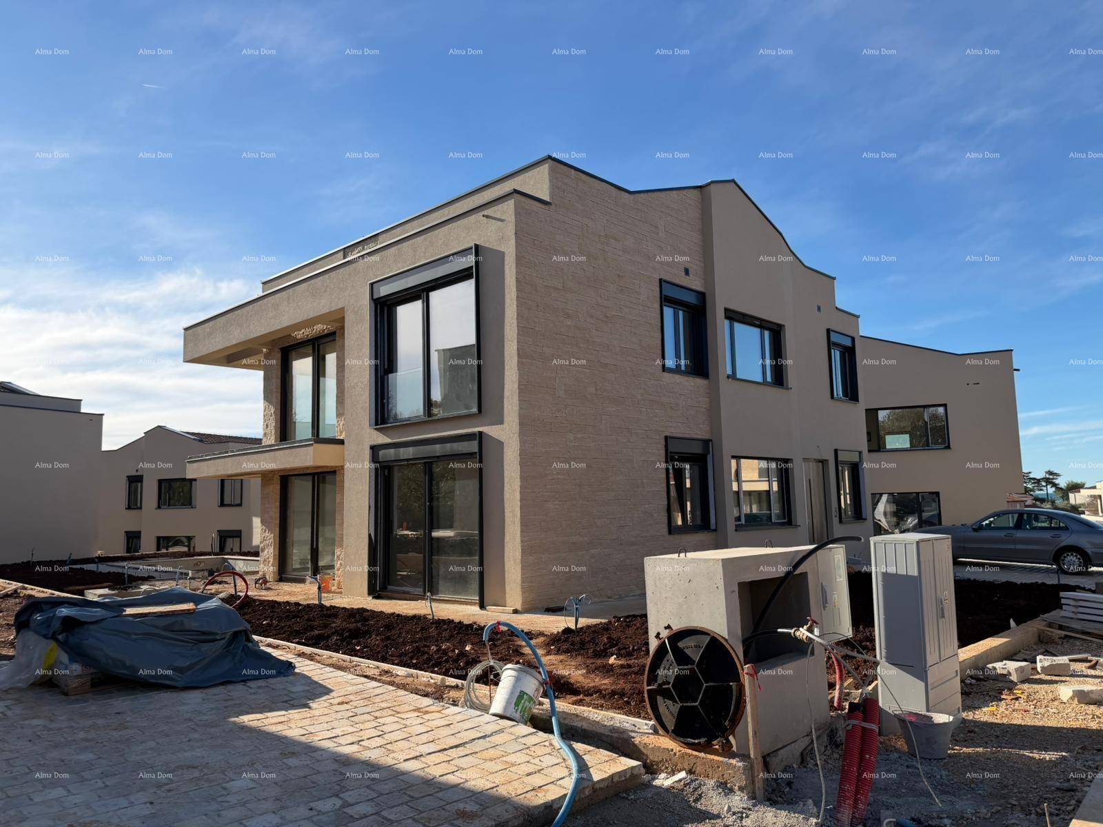 Moderne Villa im Bau mit beiger Fassade, großen Fenstern und umliegender Baustelle.