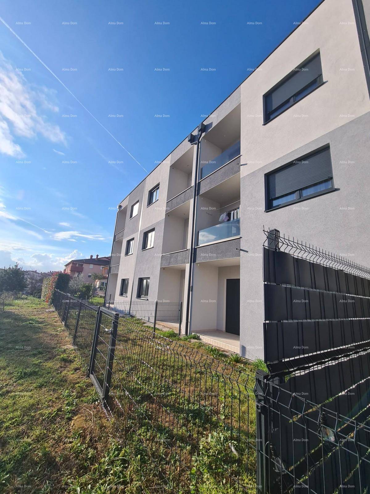 Modernes Mehrfamilienhaus mit Balkonen und angrenzender Grünfläche unter blauem Himmel.