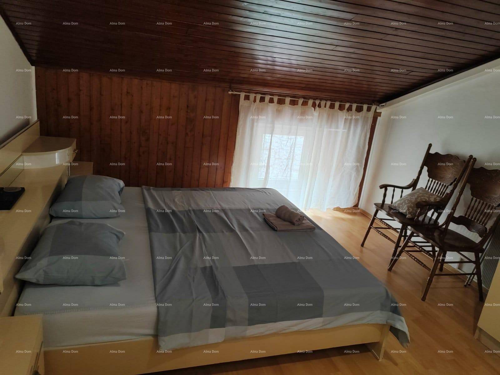 Schlafzimmer mit Doppelbett, Holzboden, Holzdecke und Fenster mit Vorhängen.