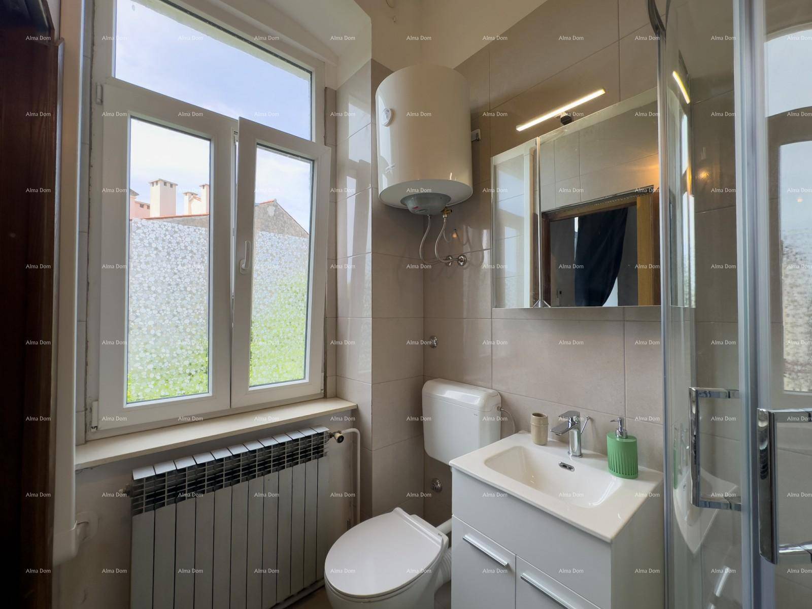 Helles Badezimmer mit Fenster, Duschkabine, Toilette und Waschbeckenunterschrank.
