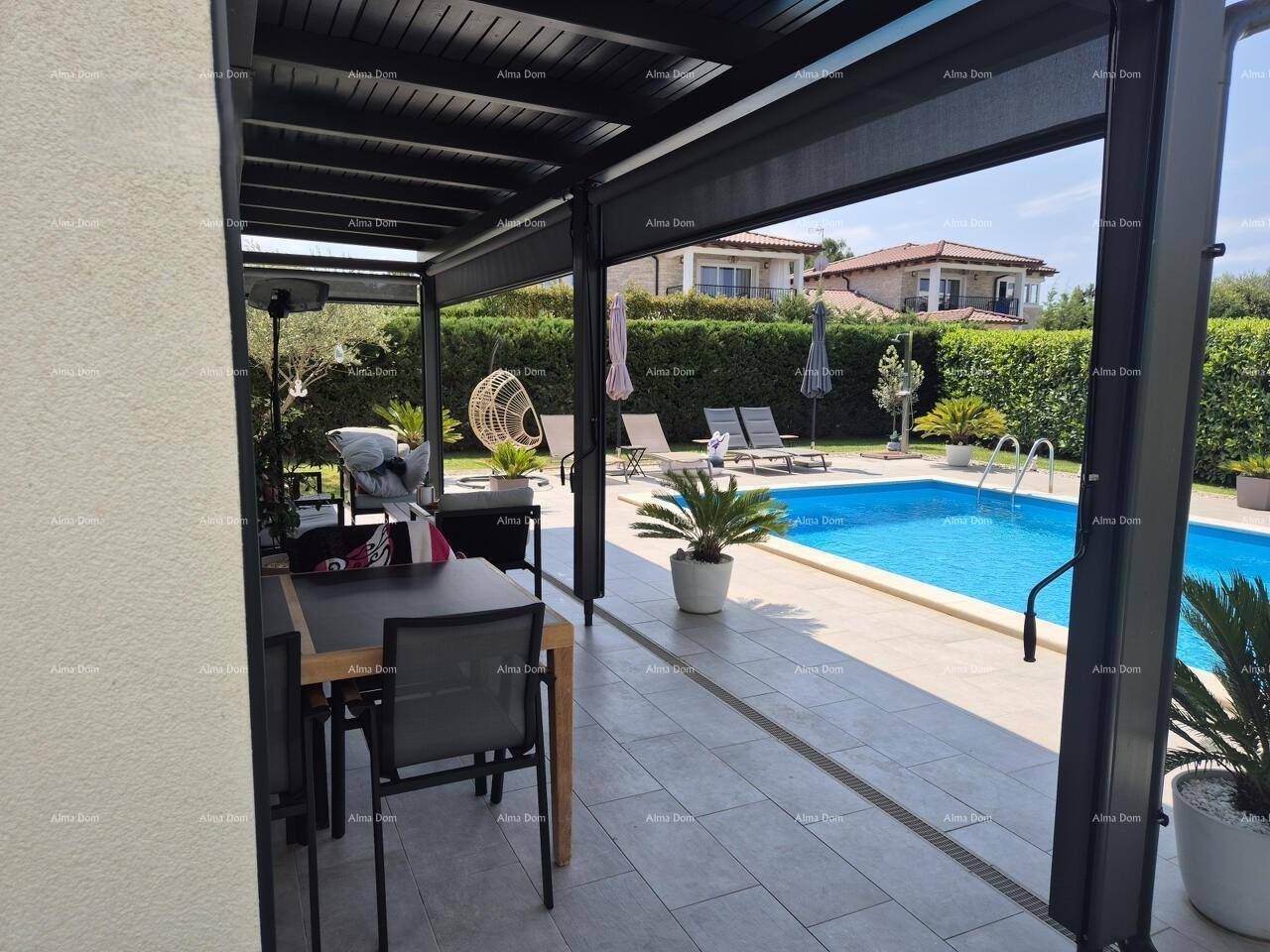 Blick von der überdachten Terrasse auf den privaten Pool und die umliegende grüne Landschaft.