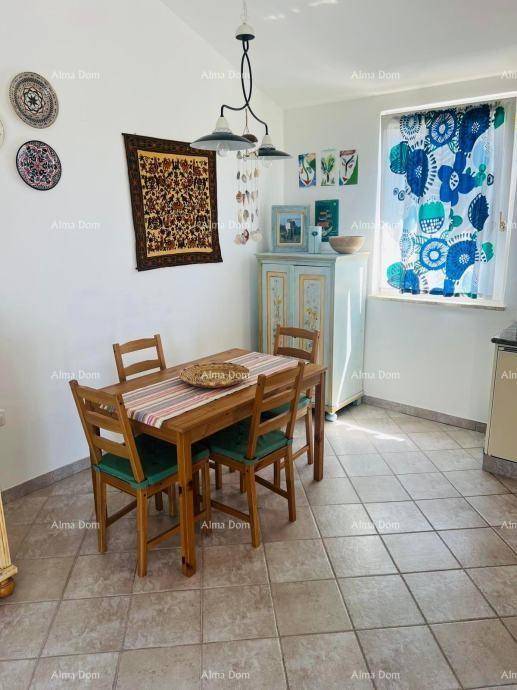 Essbereich in der Küche mit Holztisch und Stühlen, dekoriert mit bunten Vorhängen und Wandbildern.