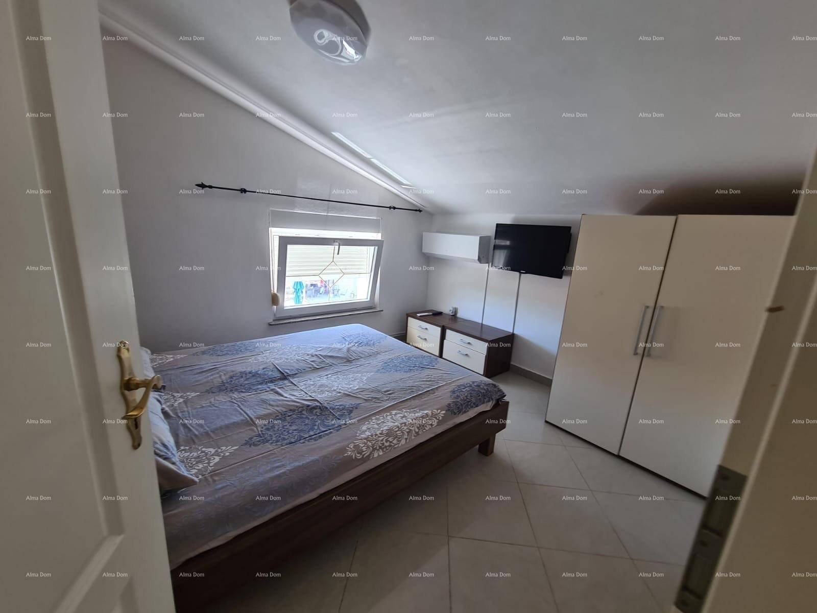 Schlafzimmer mit Bett, Kleiderschrank und Fenster, das viel Licht hereinlässt.