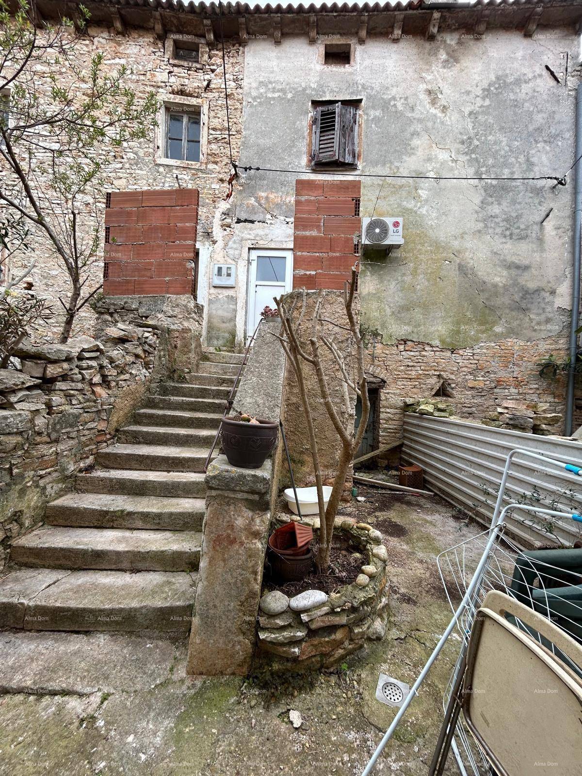Außenansicht eines alten Gebäudes mit Steintreppe und einem kleinen, bepflanzten Gartenbereich.