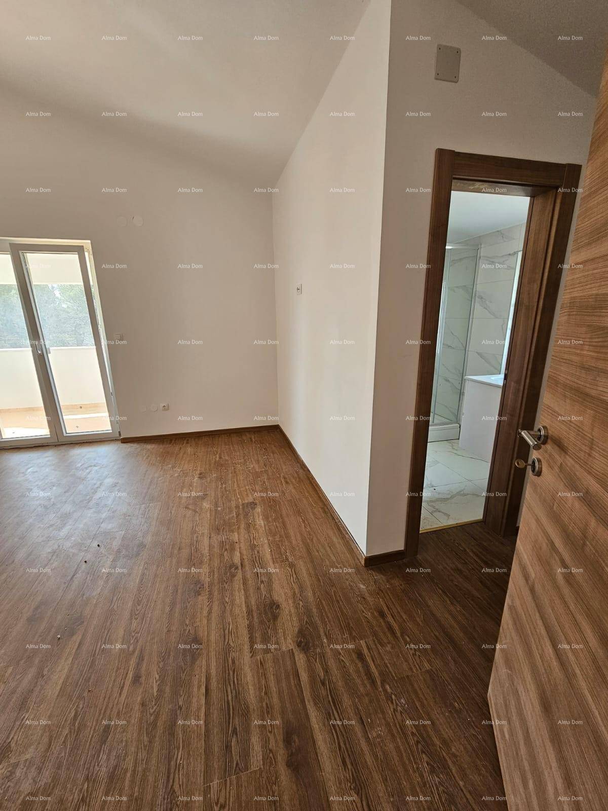 Schlafzimmer mit Laminatboden und Zugang zu einem angrenzenden Badezimmer.