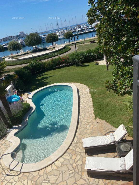 Vogelperspektive des Pools mit Sonnenliegen und dem Yachthafen im Hintergrund.