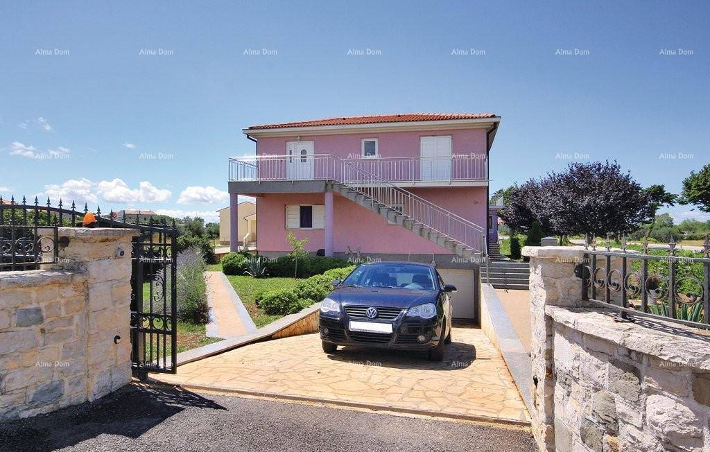 Rosa gestrichenes Haus mit Außentreppe und gepflasterter Einfahrt.