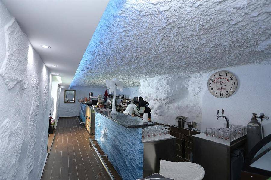 Moderne Bar mit einzigartiger, strukturierter Decke und Wänden, beleuchtet mit blauem LED-Licht.