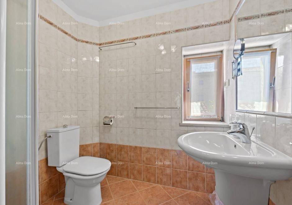 Helles Badezimmer mit Dusche, WC, Waschbecken und Fenster, in beigen Fliesen gehalten.