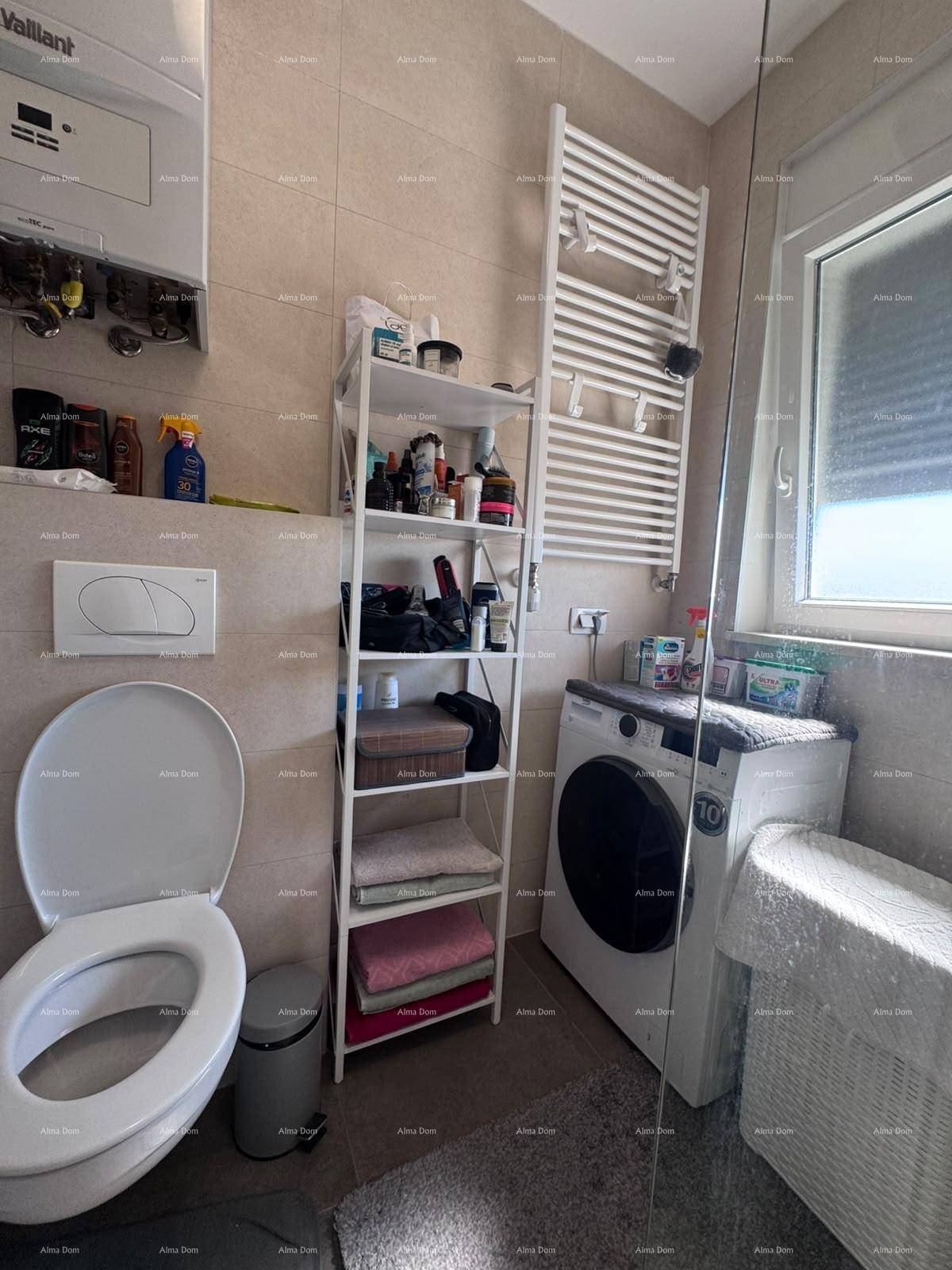 Funktionales Badezimmer mit Toilette, Waschmaschine, Regal und beheiztem Handtuchhalter.