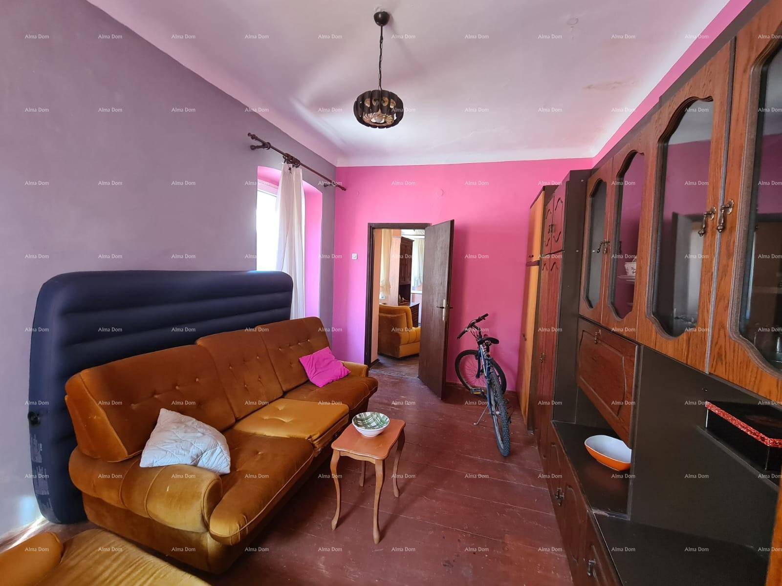Geräumiges Wohnzimmer mit pinkfarbenen Wänden, dunklen Holzmöbeln und einem braunen Sofa.