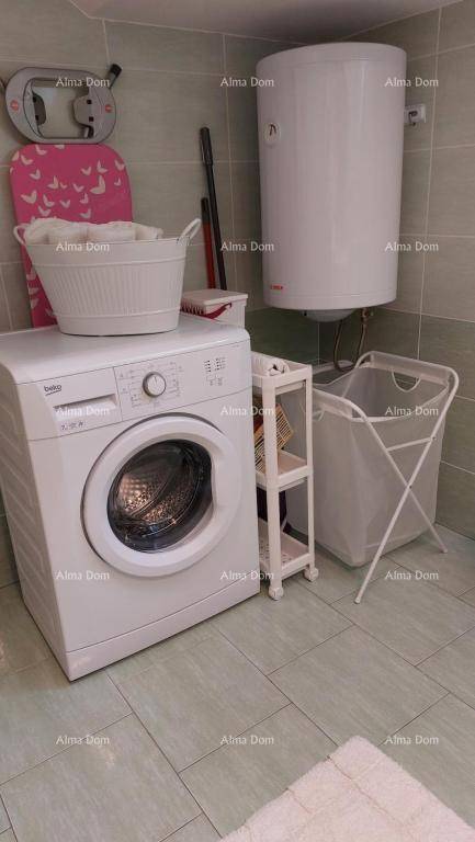 Hauswirtschaftsbereich mit Waschmaschine, Warmwasserbereiter und Wäschekorb.
