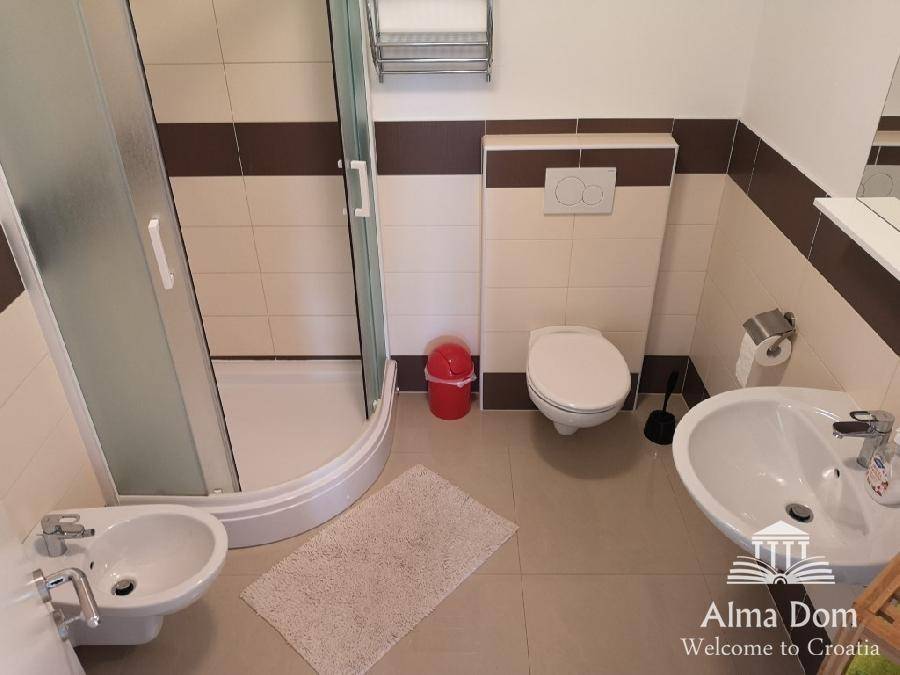 Geräumiges Badezimmer mit Duschkabine, Bidet, Toilette und Waschbecken.
