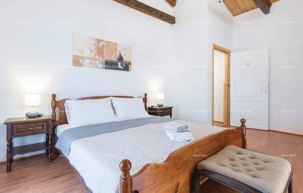 Schlafzimmer mit Holzbalkendecke, Doppelbett und Holzboden.