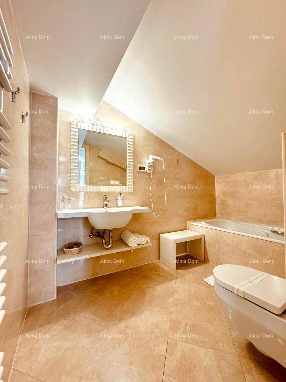 Geräumiges Badezimmer mit Badewanne, Waschtisch und Dachschräge, ausgestattet mit hellen Fliesen.