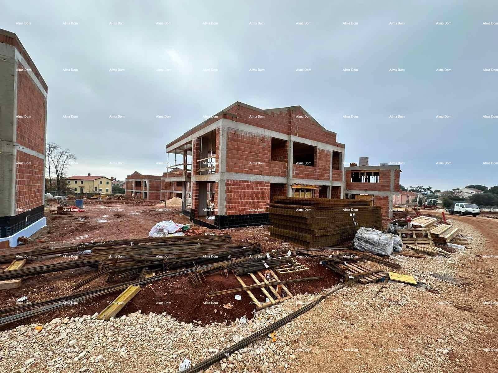 Baustelle mit mehreren Rohbauten und Baumaterialien im Vordergrund.