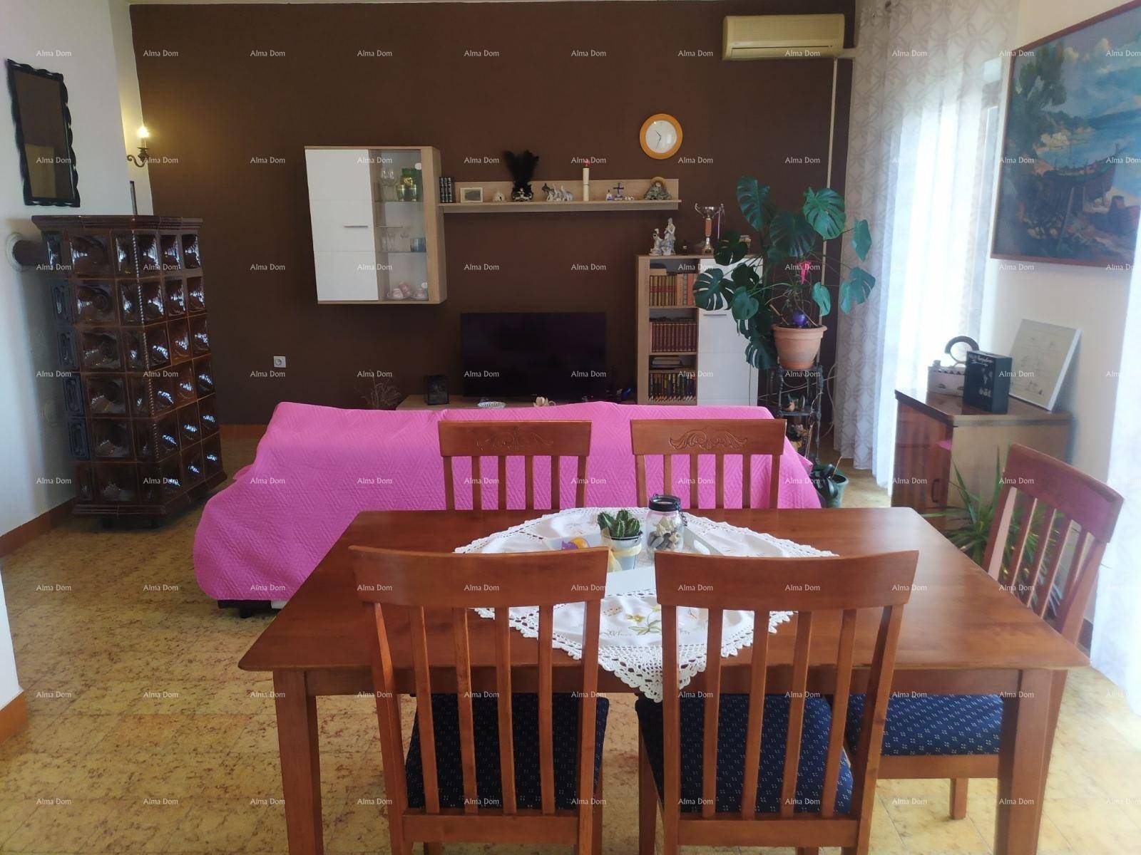 Geräumiger Wohn- und Essbereich mit braunen Wänden, Holztisch und rosa Sofa, gut beleuchtet.