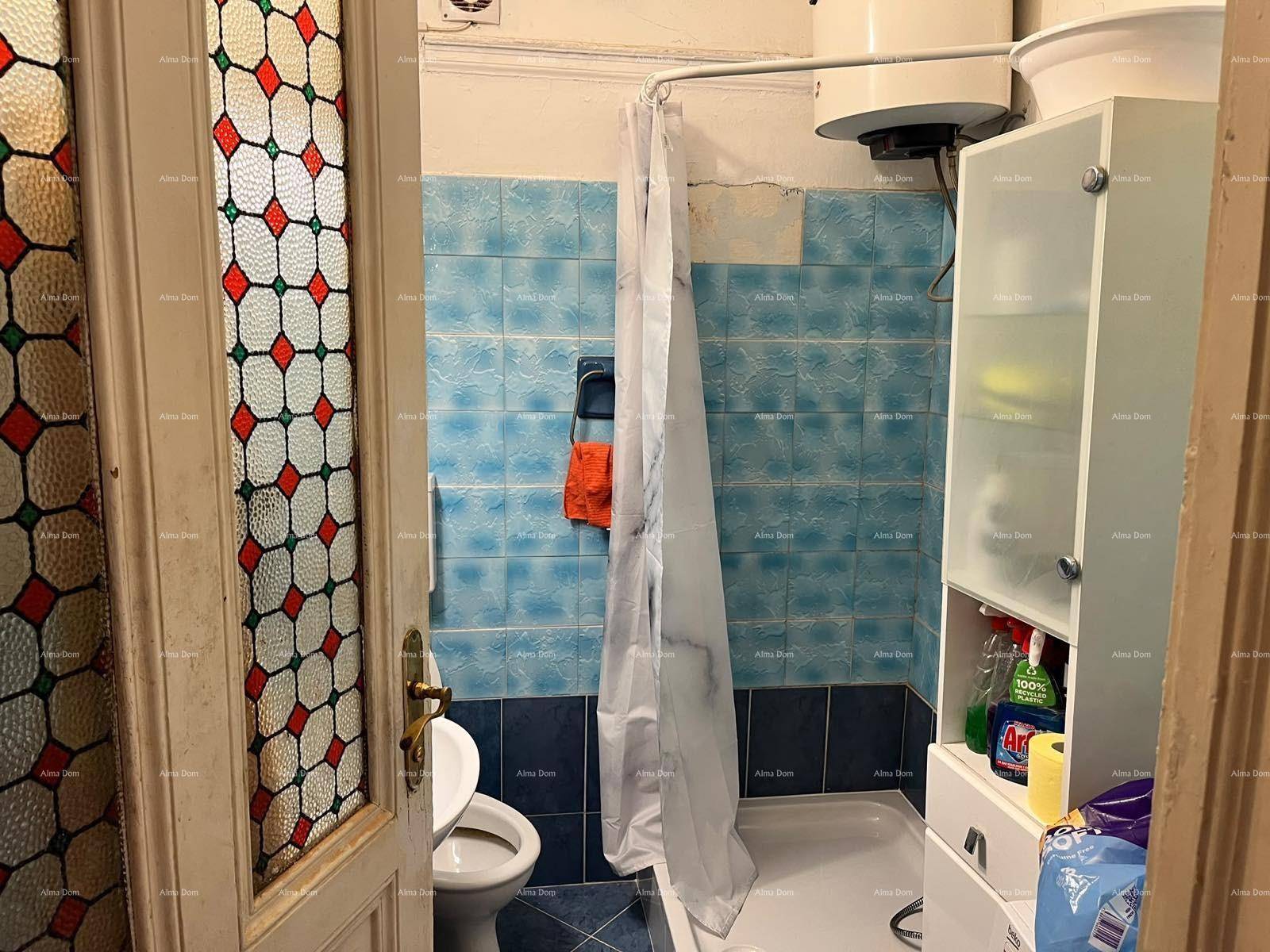 Badezimmer mit blauen Fliesen, Toilette und Duschbereich, durch eine bunte Glastür zugänglich.