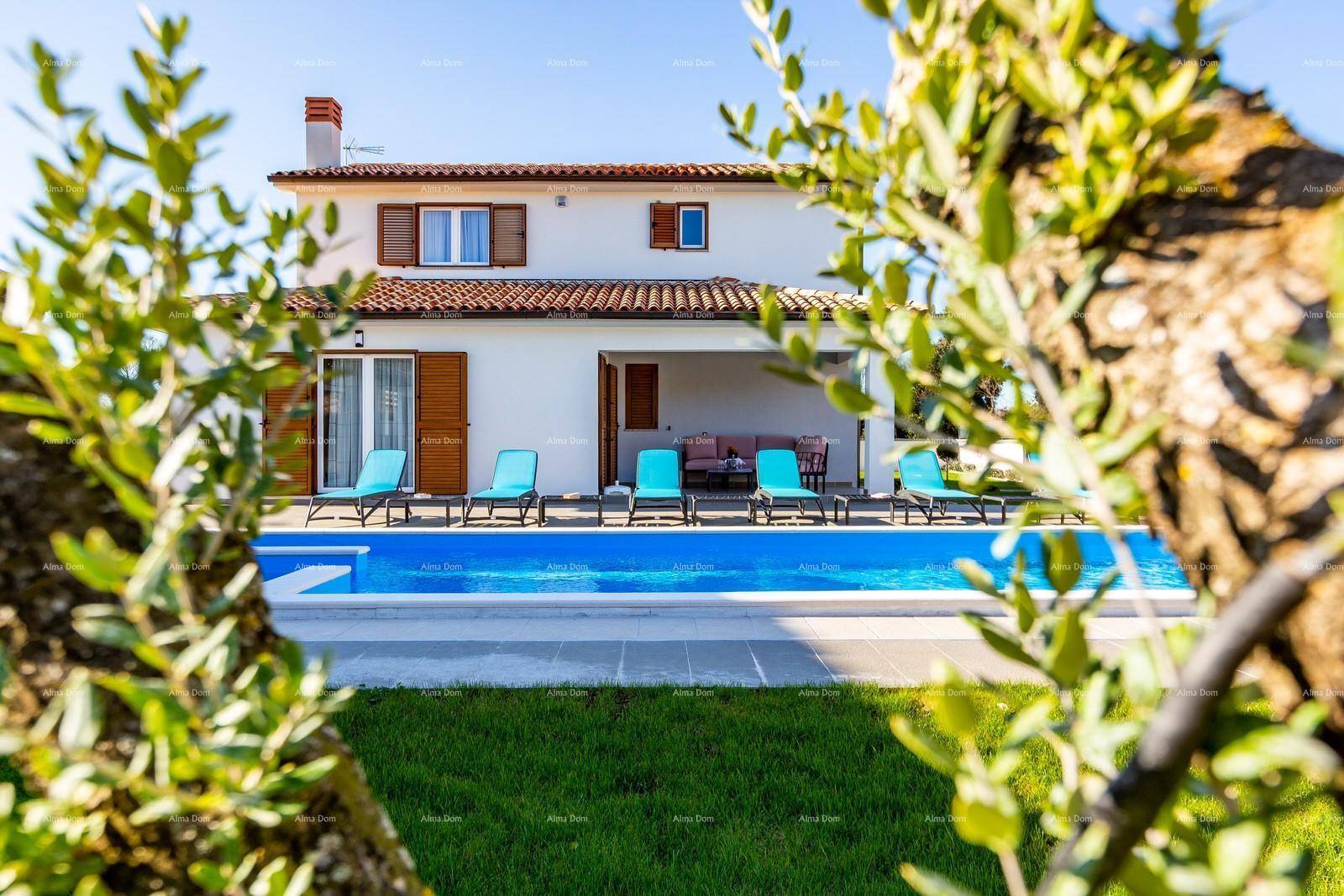 Weißes Haus mit Pool und Liegestühlen, umgeben von grüner Vegetation unter blauem Himmel.
