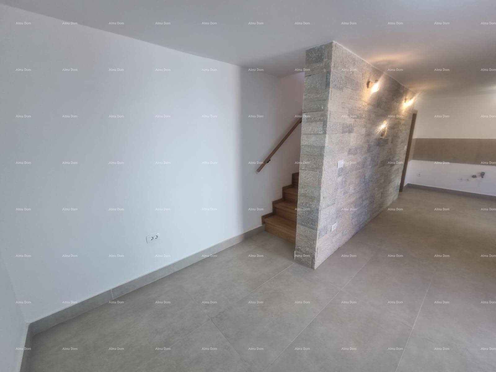 Heller Eingangsbereich mit grauen Fliesen, einer Steinwand und Holztreppe.
