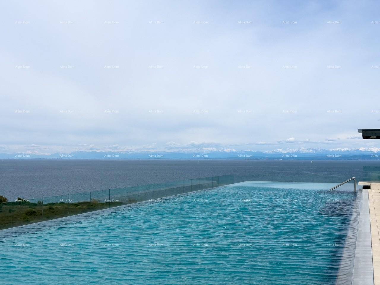 Infinity-Pool mit weitem Blick auf das Meer und die entfernten Berge unter einem bewölkten Himmel.