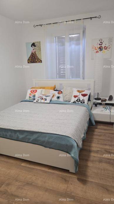 Schlafzimmer mit Doppelbett, Holzboden und Fenster, dekoriert mit modernen Bildern.