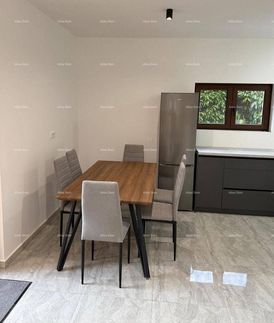 Essbereich mit Holztisch und grauen Stühlen, angrenzend an eine moderne Küche mit Kühlschrank.