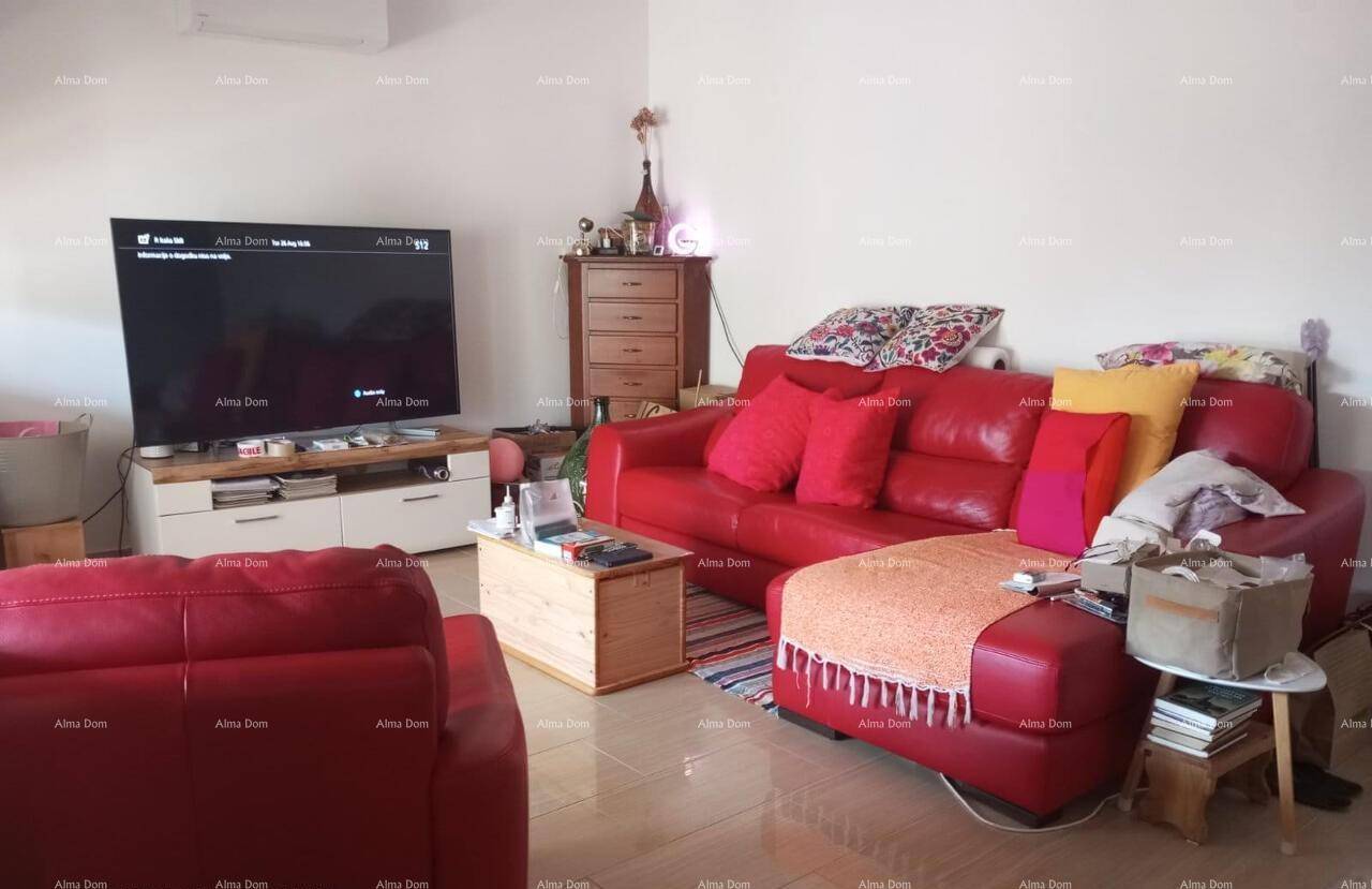 Gemütliches Wohnzimmer mit roten Ledersofas, einem Fernseher und hellen Fliesen.