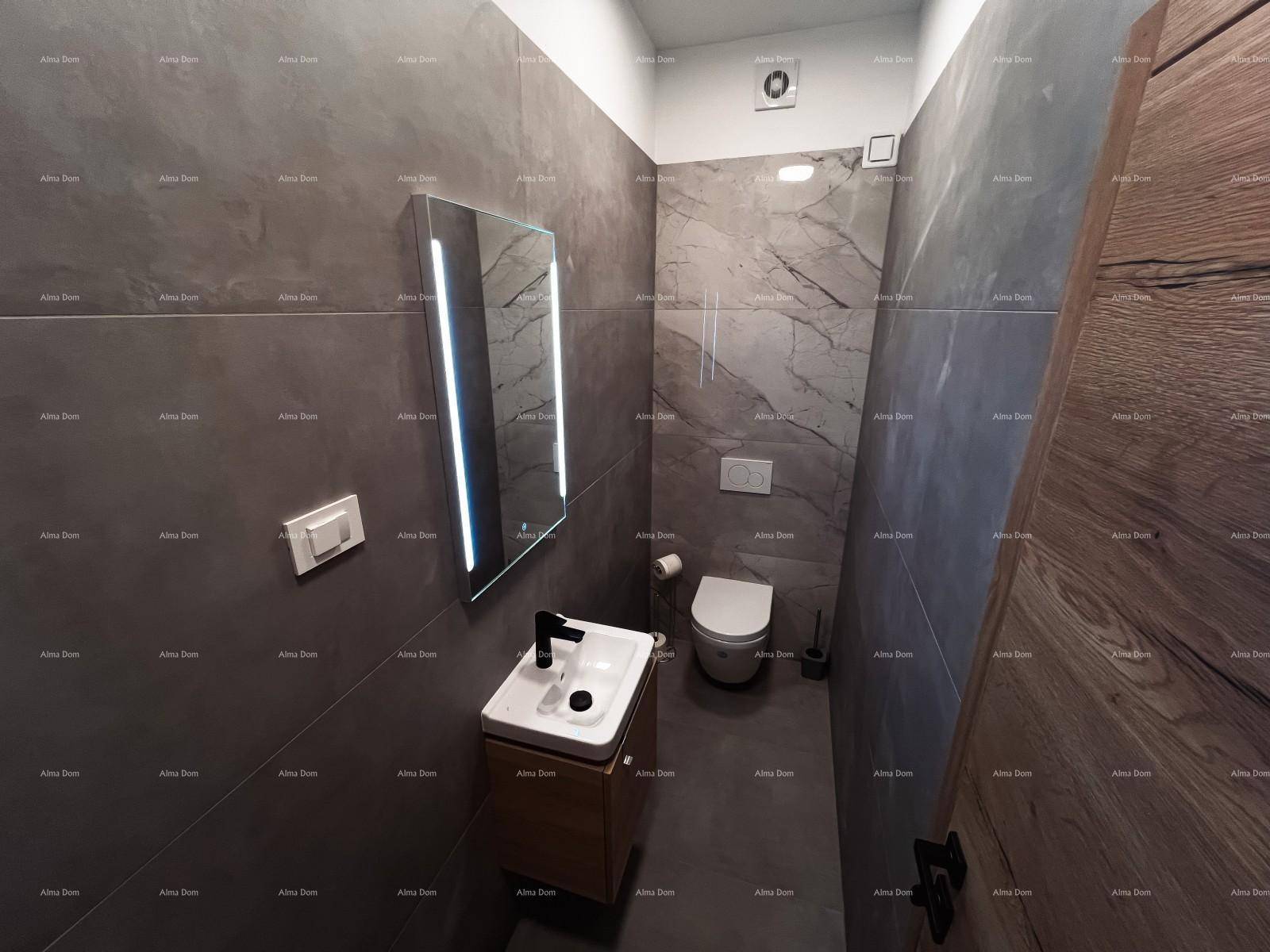 Modernes Gäste-WC mit dunklen Fliesen, beleuchtetem Spiegel und Wand-WC.