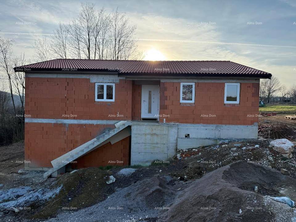 Rohbau des Hauses bei Sonnenuntergang, mit sichtbaren Ziegelwänden und Treppenzugang zum Eingang.
