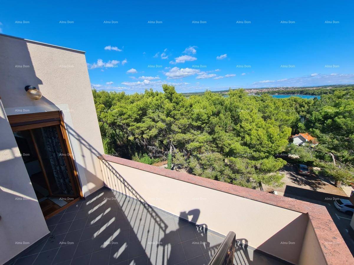 Balkon mit Geländer und Fliesenboden, bietet einen weiten Blick auf grüne Wälder und das Meer.