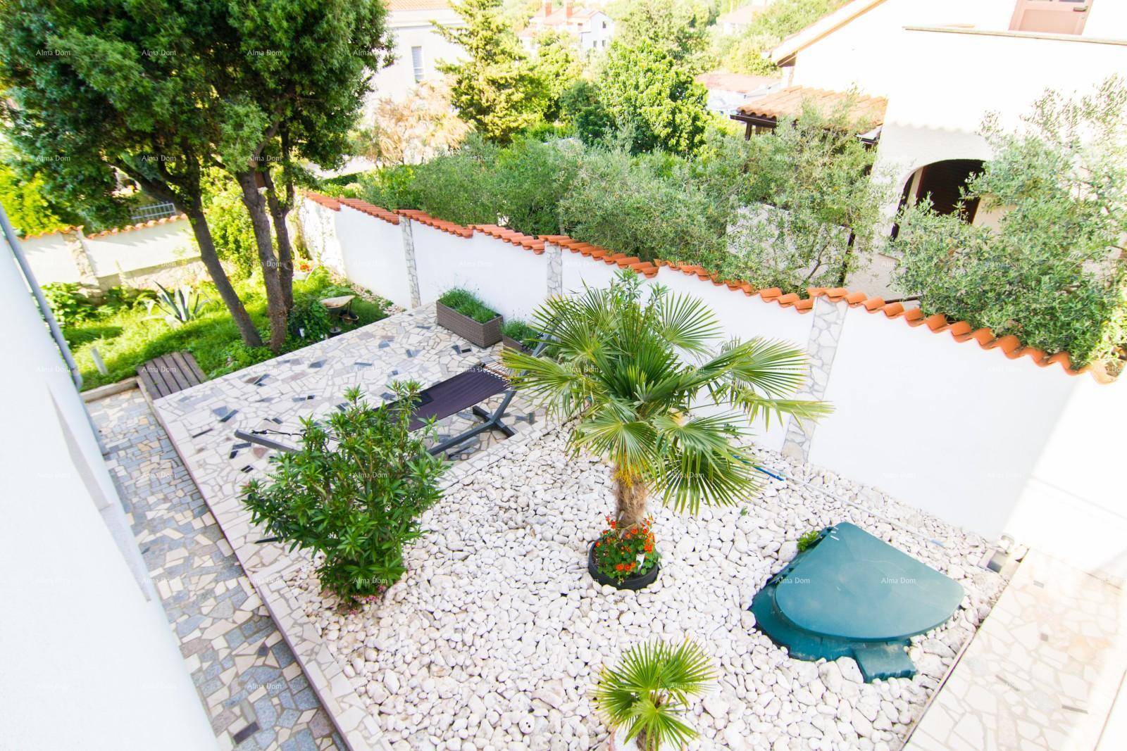 Mediterraner Garten mit weißen Kiesflächen, Palmen und einer Sonnenliege, umgeben von einer Mauer.