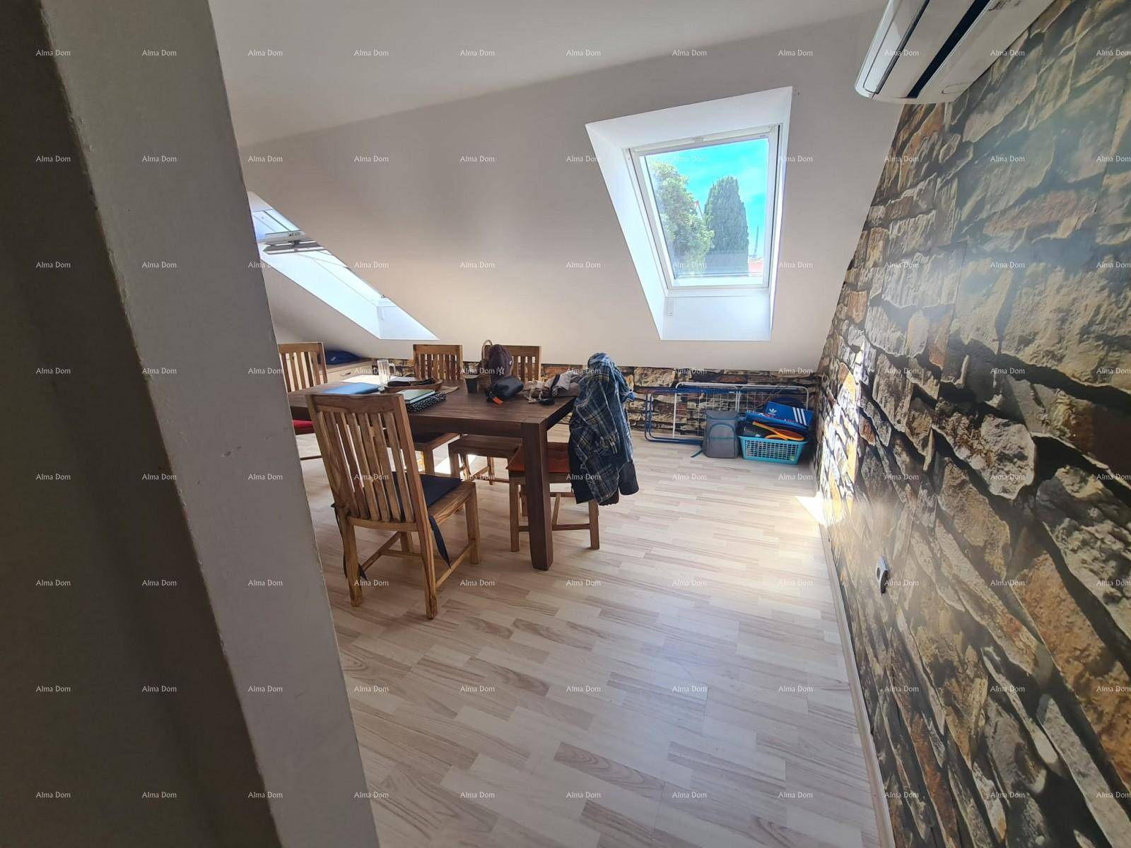 Geräumiger Essbereich im Dachgeschoss mit markanter Steinwand und großem Dachfenster für viel Licht.