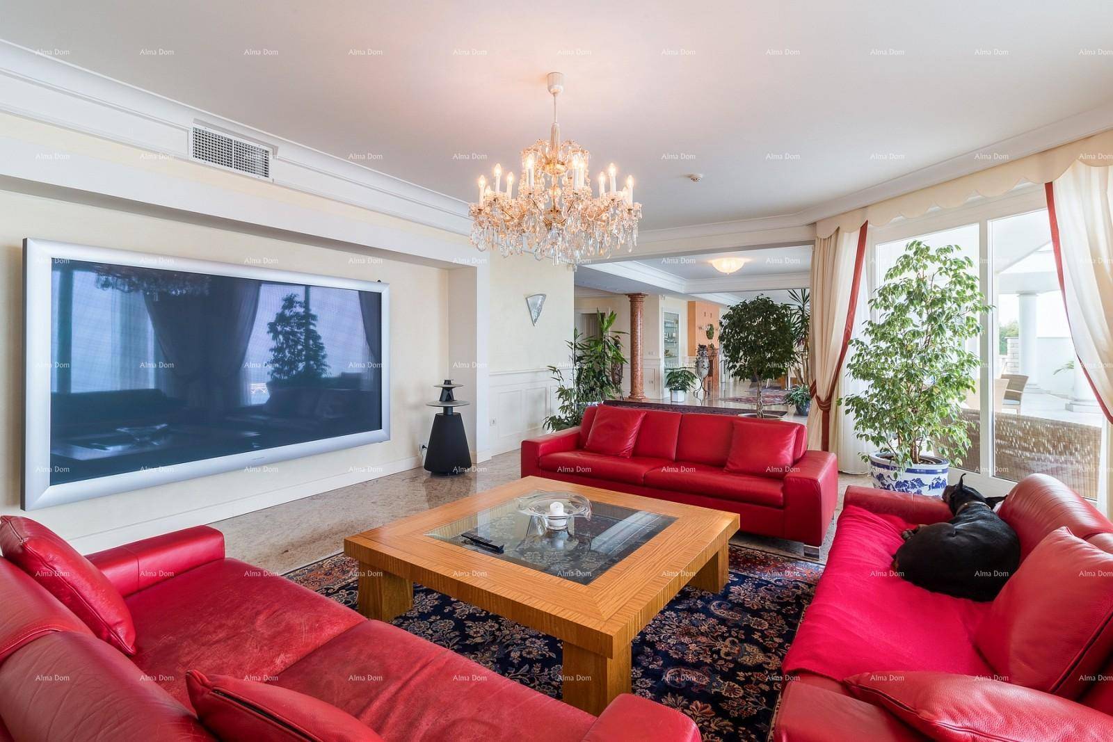 Elegantes Wohnzimmer mit rotem Ledersofa, großem Fernseher und Kronleuchter.