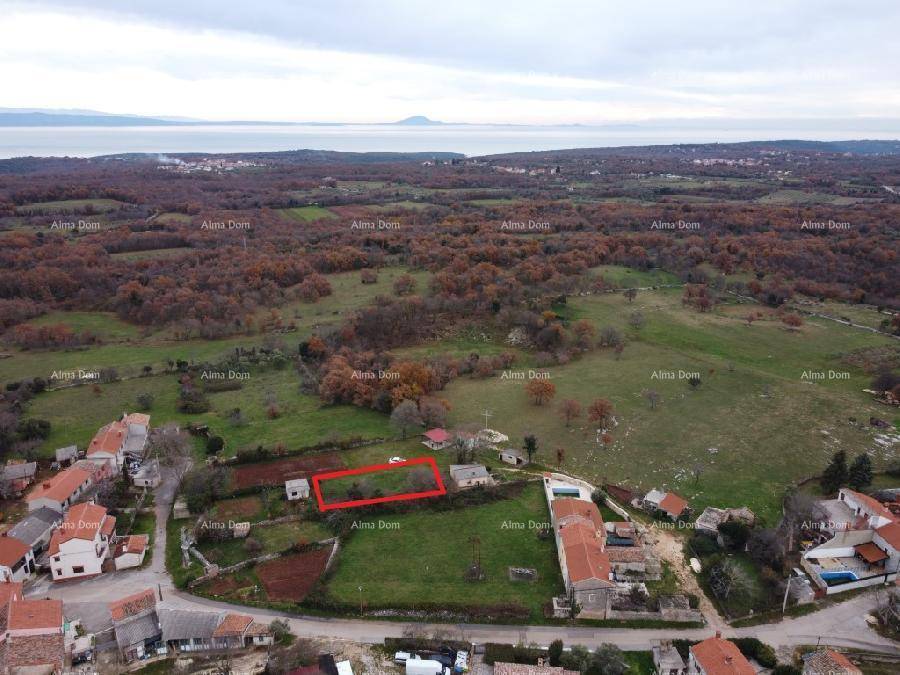Weitläufige Luftaufnahme einer ländlichen Landschaft mit Meerblick und einem markierten Grundstück in der Ferne.