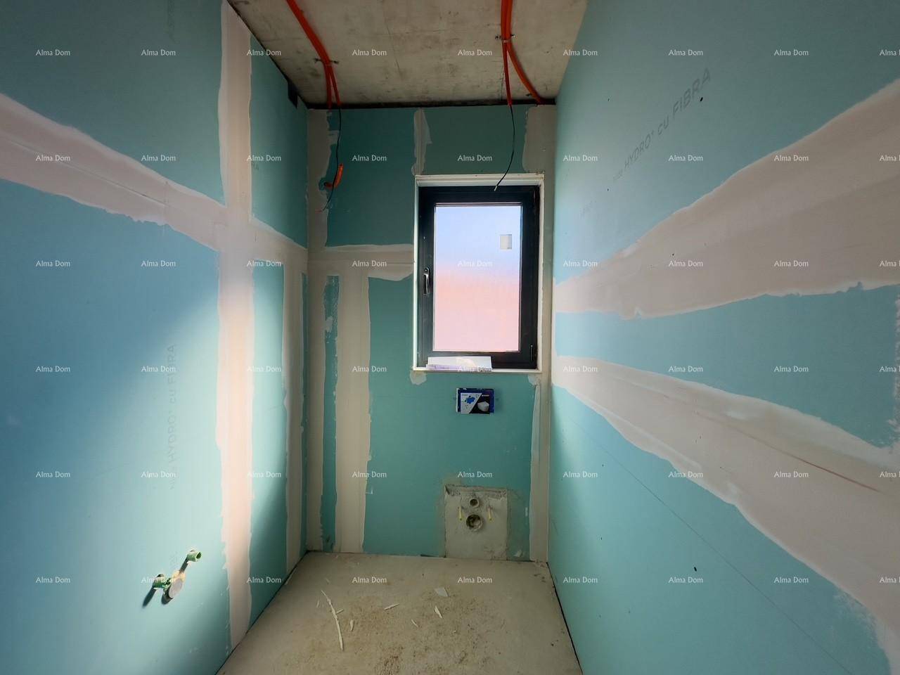 Badezimmer im Rohbau mit blauen Trockenbauwänden, Fenster und vorbereiteten Anschlüssen für Sanitärinstallationen.
