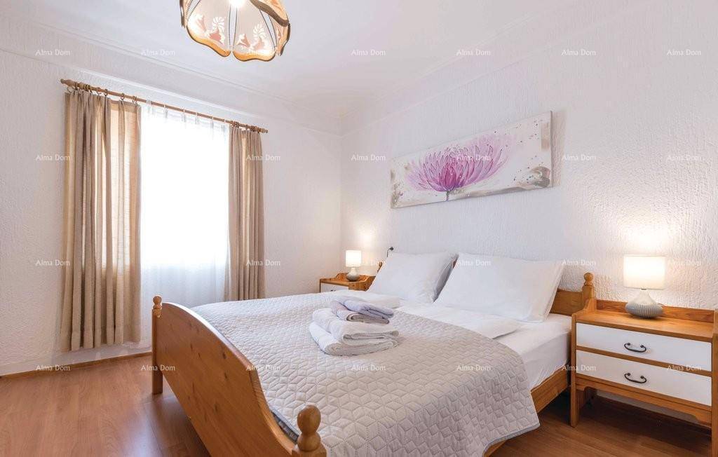 Helles Schlafzimmer mit Holzboden, Doppelbett und großem Fenster mit Vorhängen.