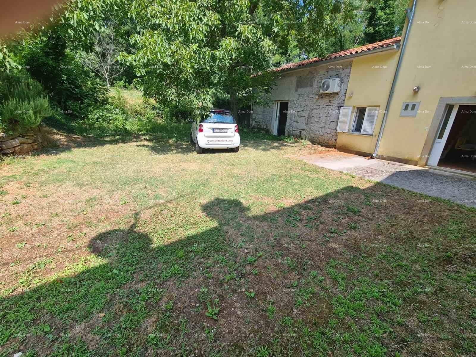 Weitläufiger Vorgarten mit geparktem Auto und den beiden Gebäudeteilen, umgeben von Natur.