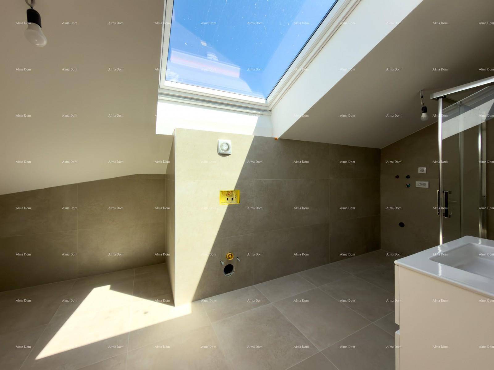 Modernes Badezimmer mit grauen Fliesen, großem Oberlicht und schräger Decke.